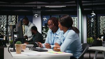 svart kvinnor arbetssätt tillsammans med data insikter på skrivbordet i arbetsyta, utvecklande företag lösningar med strategi planera och prestanda metrik analys för ny mål prestation. kamera a. video