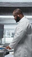 Vertical Black doctor conducting analysis with AI machine learning in laboratory, collecting research data and testing a new drug formula. Observing treatment effects and health reactions. Camera A. video