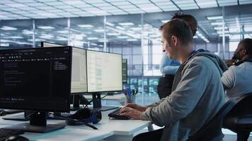 man arbetssätt i server nav kapabel av bearbetning omfattande belopp av data. den programmerare på pc skrivbord skriver på tangentbord, uppdatering servrar kontrollerande nätverk Resurser, kamera b video