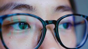 extrême proche en haut de une programmeur yeux avec code reflétant dans lunettes. une macro coup de une la personne concentré sur une ordinateur écran dans une foncé chambre. video