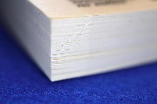 Close-up of the edge of a stack of paper or a book, showing fine details of the pages and texture against a blue background photo