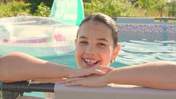 sorridente bambino godendo un' soleggiato giorno a il bordo piscina con gonfiabile squillare video