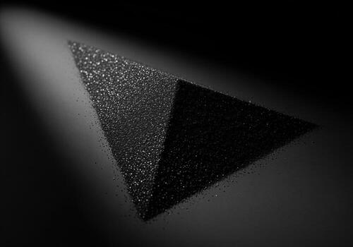 Striking black geometric form with granular texture illuminated by spotlight on dark surface photo