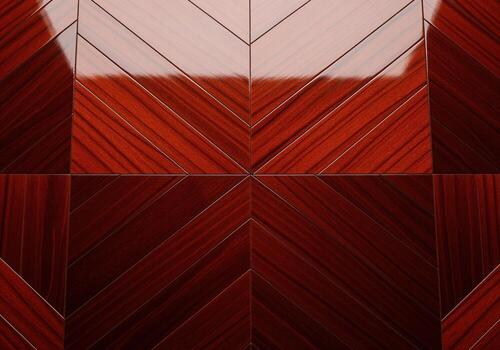 Highly polished dark cherry wood veneer surface showcasing a complex chevron pattern photo