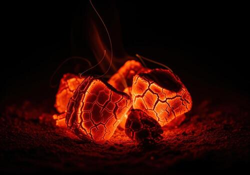Intense glowing red and orange embers of burning charcoal on a dark background photo