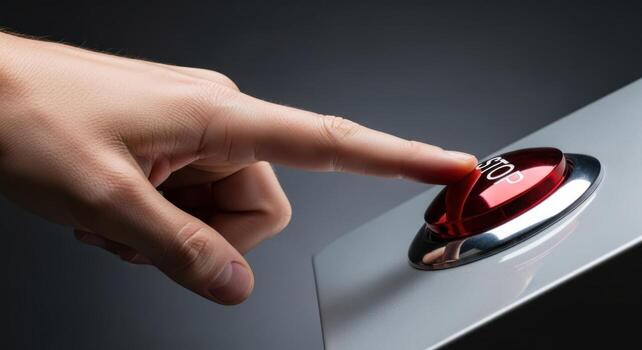 Human hand finger pressing a large glossy red stop button for emergency control photo