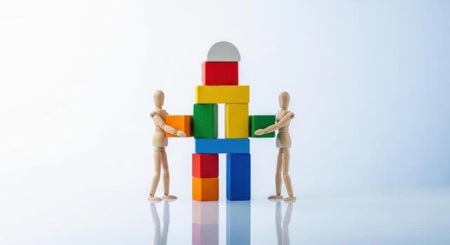 Two wooden figures building a colorful block structure, symbolizing teamwork and construction photo