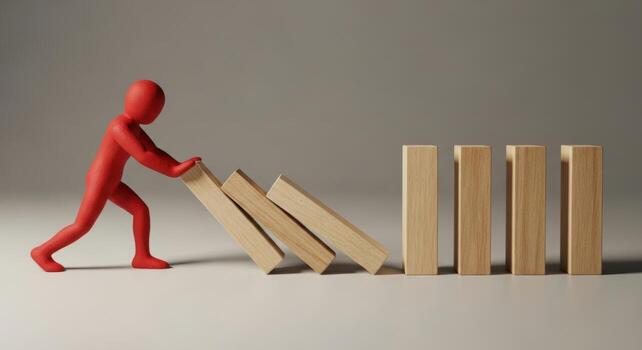 Red figure pushing wooden dominoes, illustrating a chain reaction and critical impact photo