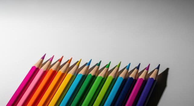 Vibrant sharpened colored pencils fanned out in a rainbow spectrum on a white surface photo