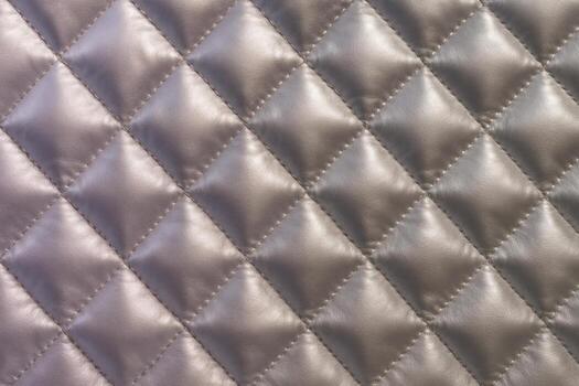 Luxurious quilted satin fabric texture with elegant diamond pattern and soft padded surface photo
