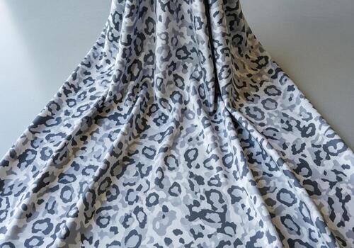 Luxurious flowing charmeuse silk fabric with elegant snow leopard camouflage pattern photo