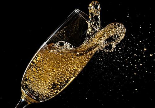 Dynamic close up of sparkling wine overflowing from a flute glass with a splash photo