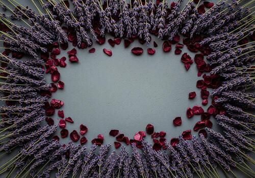 Elegant frame of violet lavender sprigs and scattered deep red rose petals on a grey surface photo