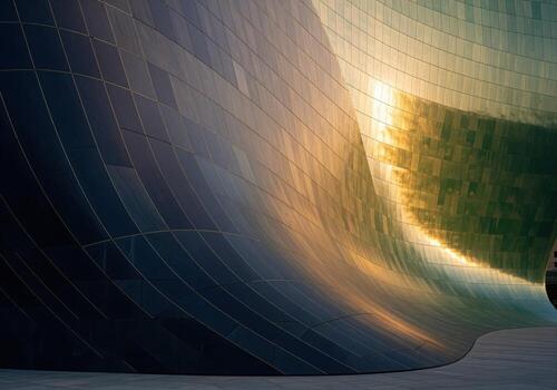 Modern sculptural facade with curved lines reflecting golden hour light on its tiled surface photo