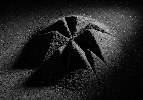 Dramatic close up of dark granular powder sculpted into abstract angular peaks photo