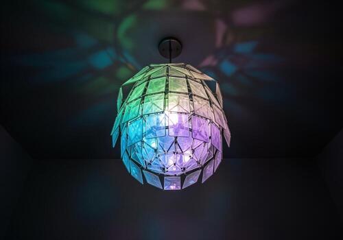 Avant garde geometric light fixture with iridescent panels casting colorful patterns photo