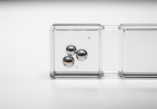 Metallic spheres shimmering in clear liquid within a transparent rectangular block photo
