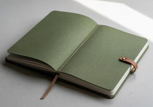 Open forest green journal with textured cover and leather strap closure photo