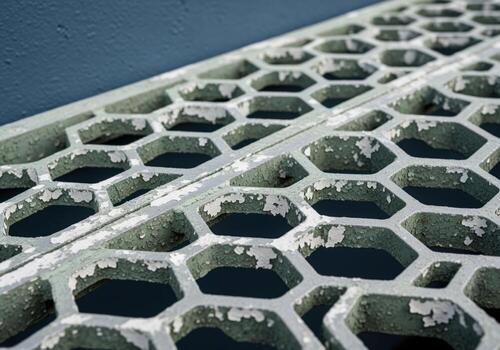 Weathered aluminum grate with hexagonal honeycomb pattern and peeling paint photo