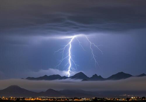 Powerful lightning bolt illuminates dark mountains and fog during a severe thunderstorm photo