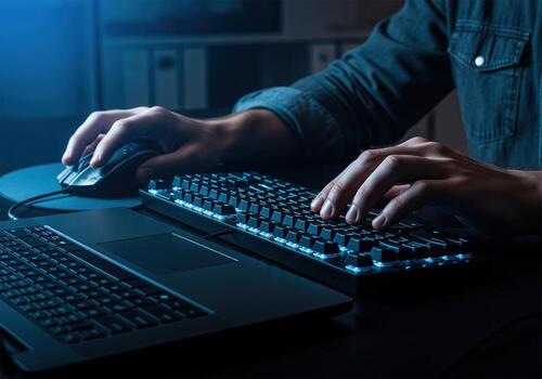 Hands typing on a backlit keyboard and using a computer mouse at a desk photo