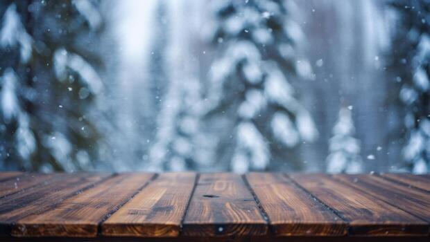 Dark wooden rustic table surface with falling snow and a blurred bokeh background of a winter forest landscape photo