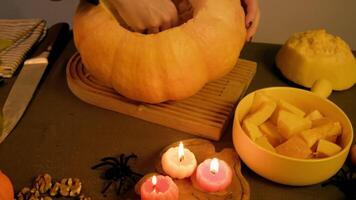 stor pumpa är placerad på skärande styrelse medan person försiktigt tar bort frön och massa från inuti använder sig av händer i stänga upp se. video