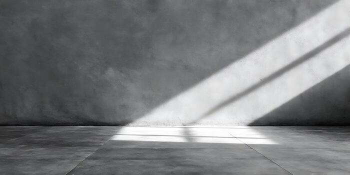 A minimalist concrete room with sunlight casting shadows on the textured gray wall and floor creating an abstract background photo