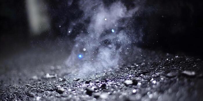 azul ligero ilumina un dramático nube de polvo y partículas que cae sobre un texturizado oscuro superficie creando un misterioso atmosférico efecto foto