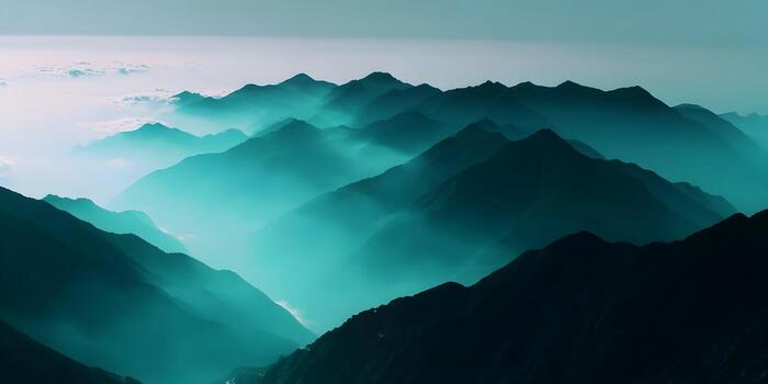 A vast mountain range is shrouded in turquoise mist and clouds creating a serene atmospheric landscape photo