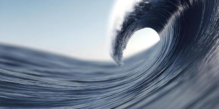 A large ocean wave dramatically curls and crests with white foam under a clear bright sky photo