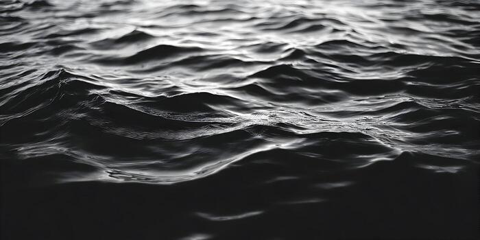 A close up monochrome view of dark water waves creating a textured abstract background photo