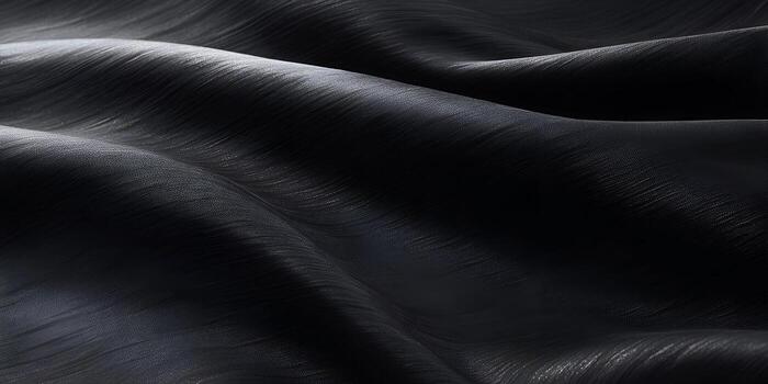 An elegant dark gray textured fabric shows undulating waves and subtle light reflections creating a sleek abstract background photo