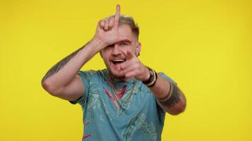 Tourist stylish guy showing loser gesture and pointing on you, blaming accusing for unsuccess, expressing disrespect, mocking your failure, bullying abuse. Young man on yellow studio wall background video