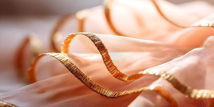 A soft peach sheer fabric with a shimmering gold ruffled edge is draped elegantly creating delicate folds and textures photo