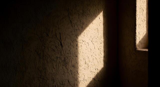 Warm morning sunlight casts dynamic triangular shadows on a rough, textured wall surface, highlighting architectural details and creating an abstract pattern photo