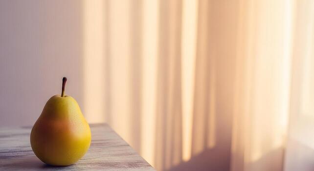 A single ripe yellow pear rests on a wooden surface with soft light filtering through a curtain in the background photo