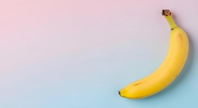 A single ripe yellow banana on a smooth gradient background with soft pink and blue hues, showcasing its natural curve and texture photo