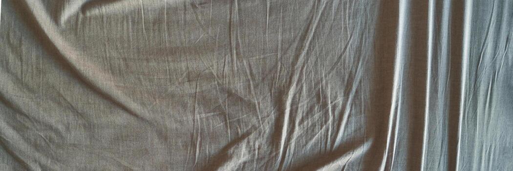 Close-up of wrinkled beige fabric texture with soft shadows and light patterns across the surface. photo