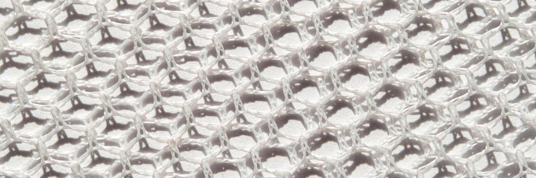 Close-up of textured white honeycomb pattern surface with hexagonal cells and shadows. photo