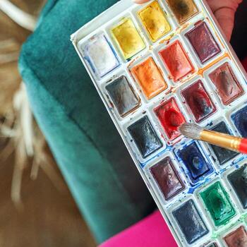 Top view of watercolor set with paintbrush creating art on vibrant palette in cozy setting. photo