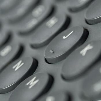 Close-up view of dark gray circular computer keyboard keys with focus on j key. photo