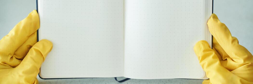 manos en amarillo caucho guantes participación abierto blanco cuaderno con punteado paginas en brillante ligero ajuste. foto