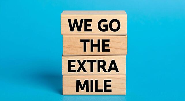 Stacked wooden blocks displaying the message We Go The Extra Mile against a bright blue background symbolizing dedication commitment and exceeding expectations in business and personal endeavors photo