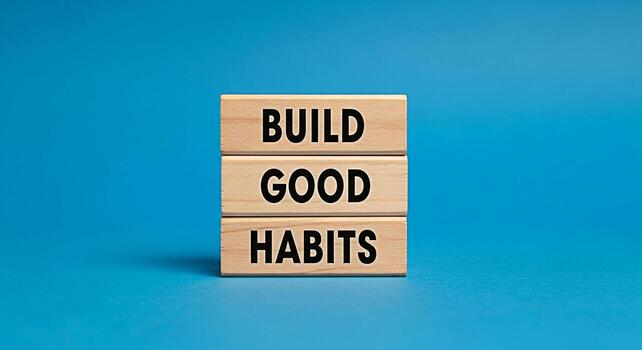 Stacked wooden blocks displaying the motivational message Build Good Habits on a vibrant blue background symbolizing selfimprovement personal growth and the positive impact of consistent routines for photo