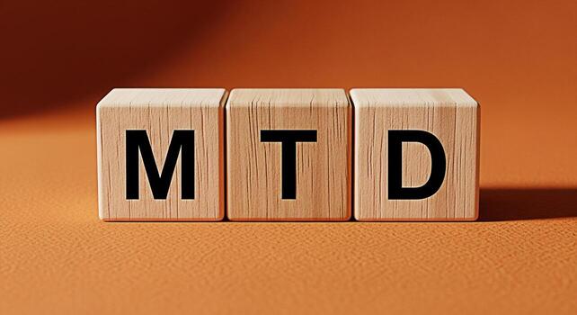 Wooden blocks displaying MTD acronym on a textured orange surface representing month to date financial performance and business analytics in a simple clean and visually appealing way photo