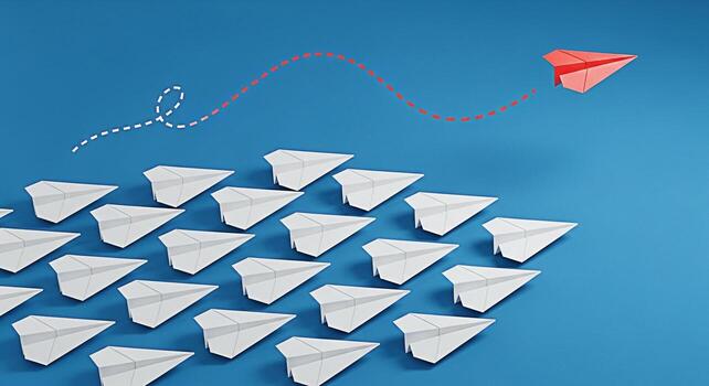 A red paper airplane soaring above a group of white paper airplanes on a blue background symbolizing leadership innovation and a unique approach to achieving success in a competitive environment photo