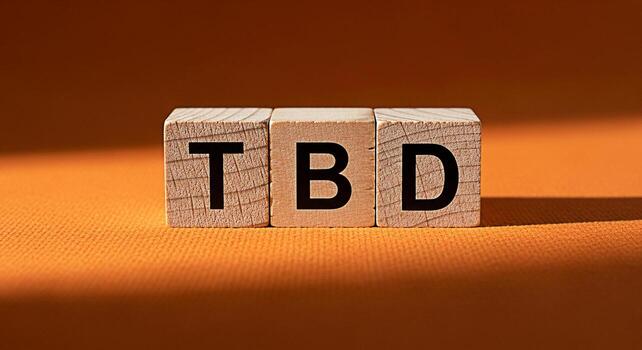 Wooden blocks displaying TBD on an orange surface casting shadows representing a concept of uncertainty anticipation and future planning in a business or project management context with a warm and inv photo