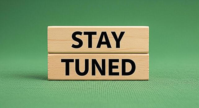 Wooden blocks stacked on a green surface displaying the phrase Stay Tuned creating anticipation and excitement for an upcoming announcement or event inviting viewers to remain attentive and engaged photo