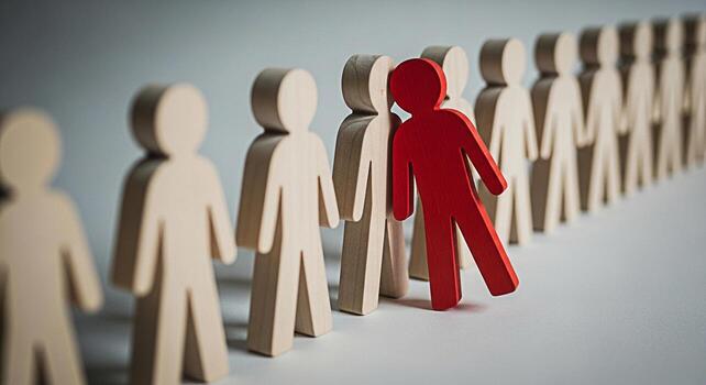 Bold red wooden figure standing out from a line of neutral figures in a minimalist setting representing individuality leadership and the courage to be different in a conformist world photo